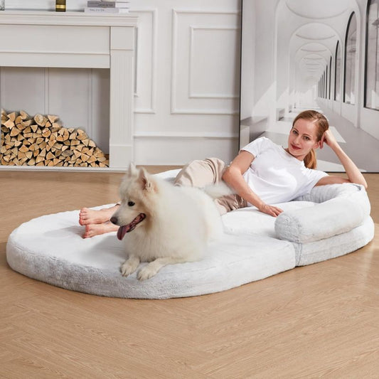 Frau und weißer Hund entspannen gemeinsam auf einem großen Bodenbett