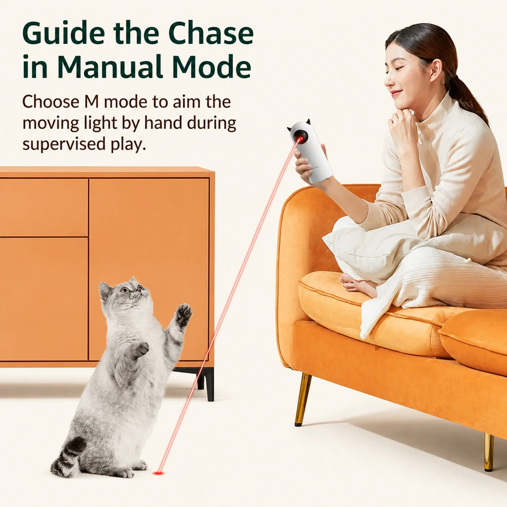 Person guiding an automatic laser cat toy in manual mode while a cat follows the light